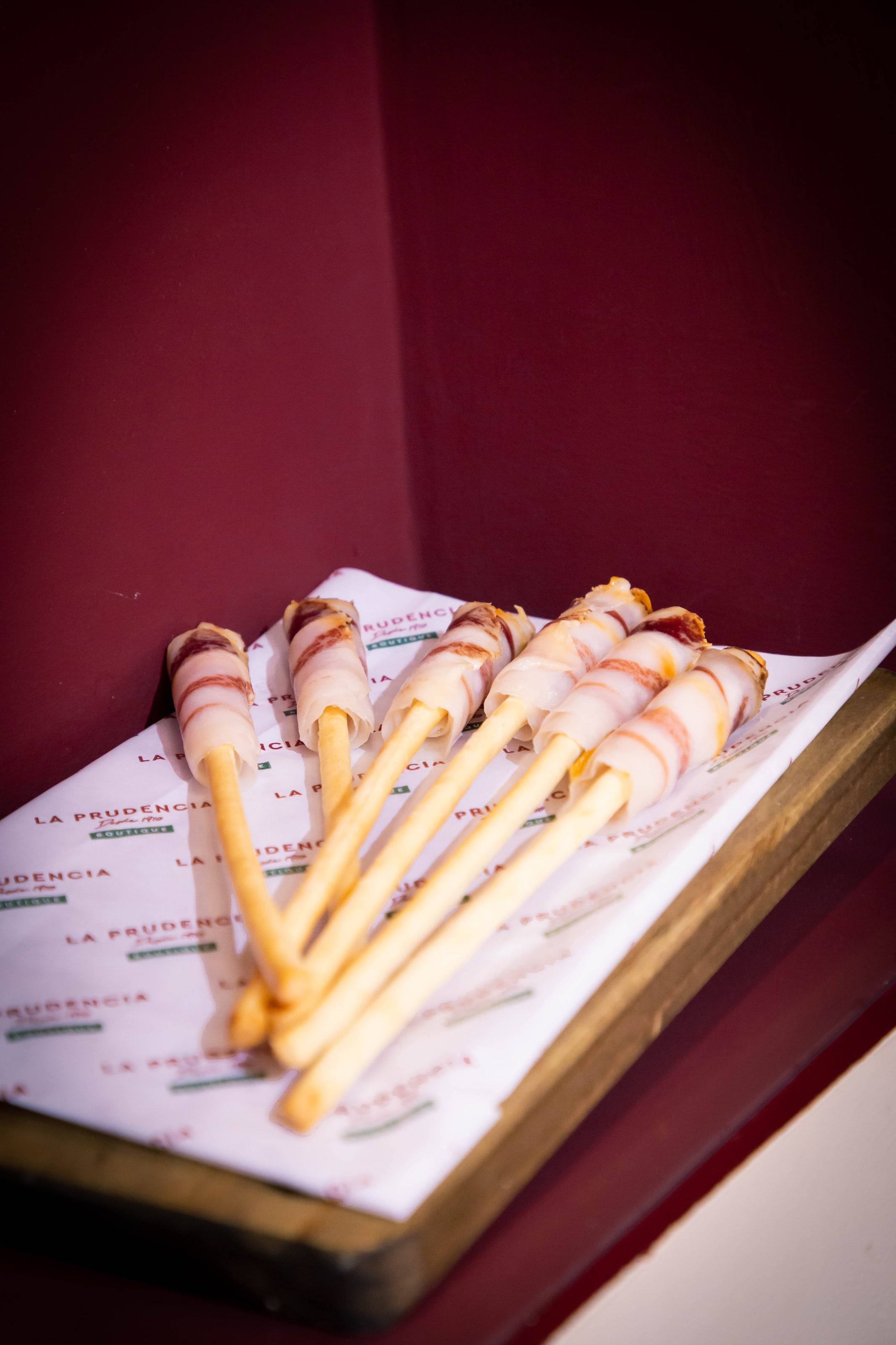 Picos de pan envueltos en jamón ibérico sobre papel de La Prudencia Boutique.