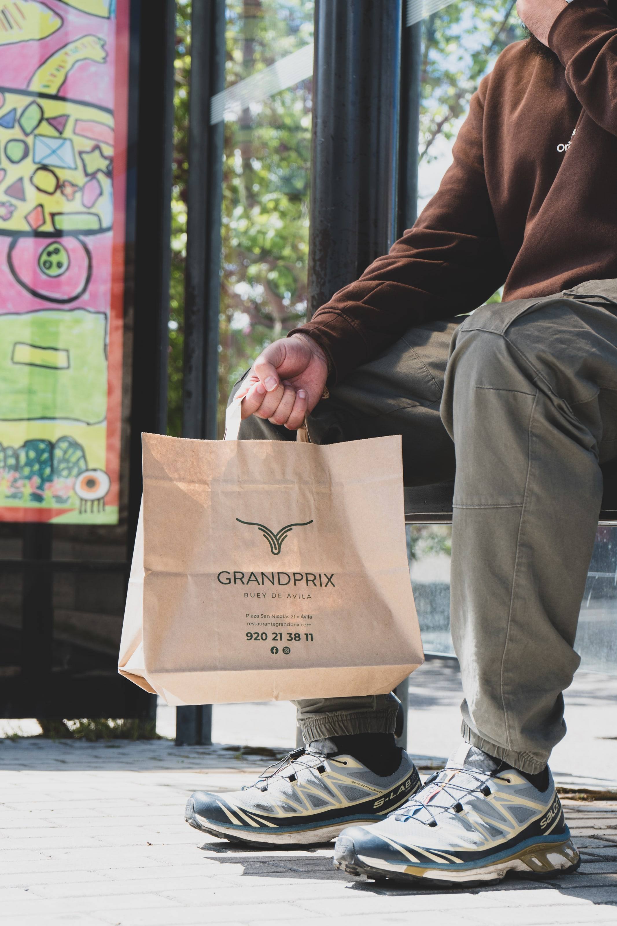 Cliente sentado con la bolsa de comida para llevar del restaurante Grand Prix.