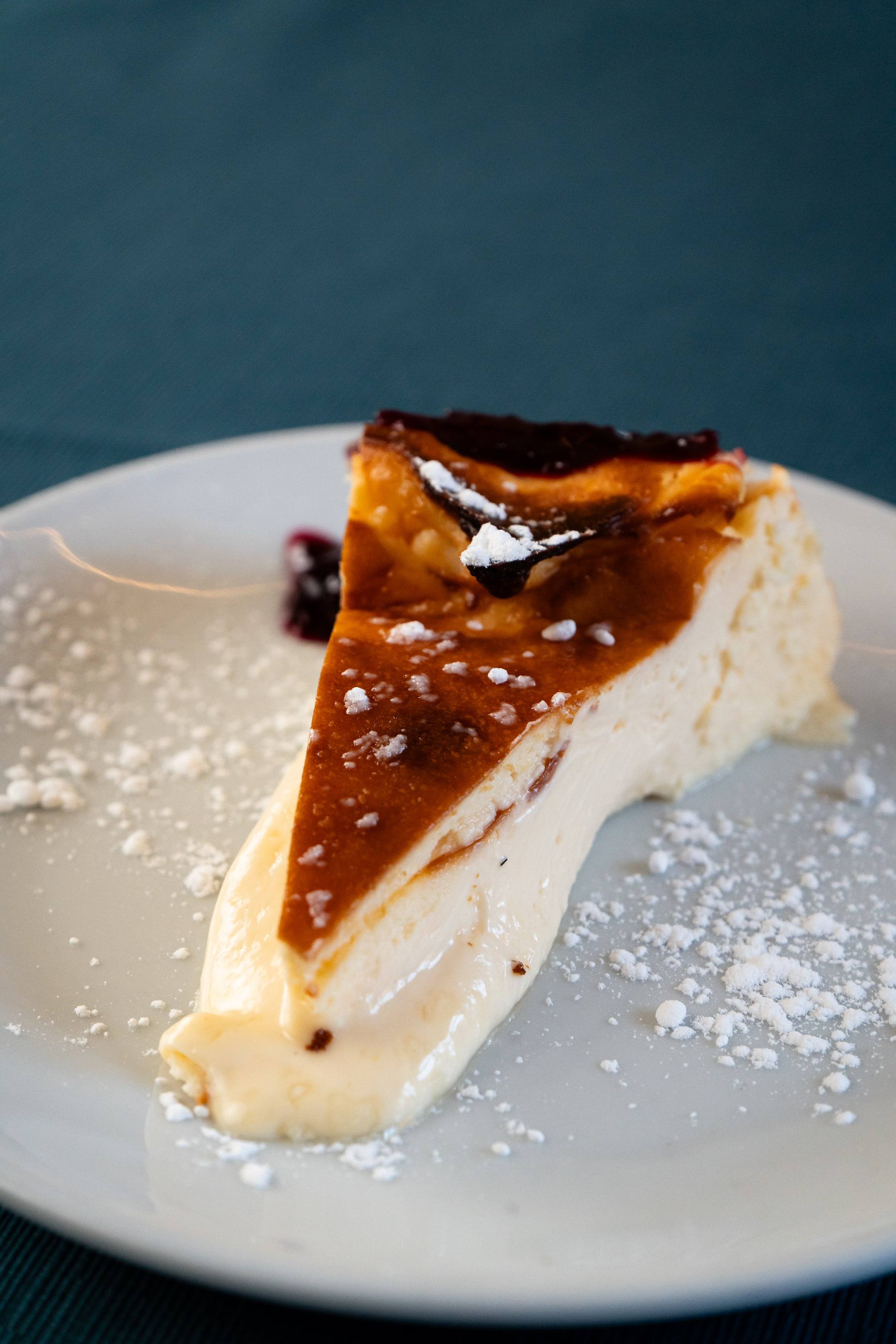 Porción de tarta de queso con azúcar glas y frutos rojos en el restaurante Raíces.